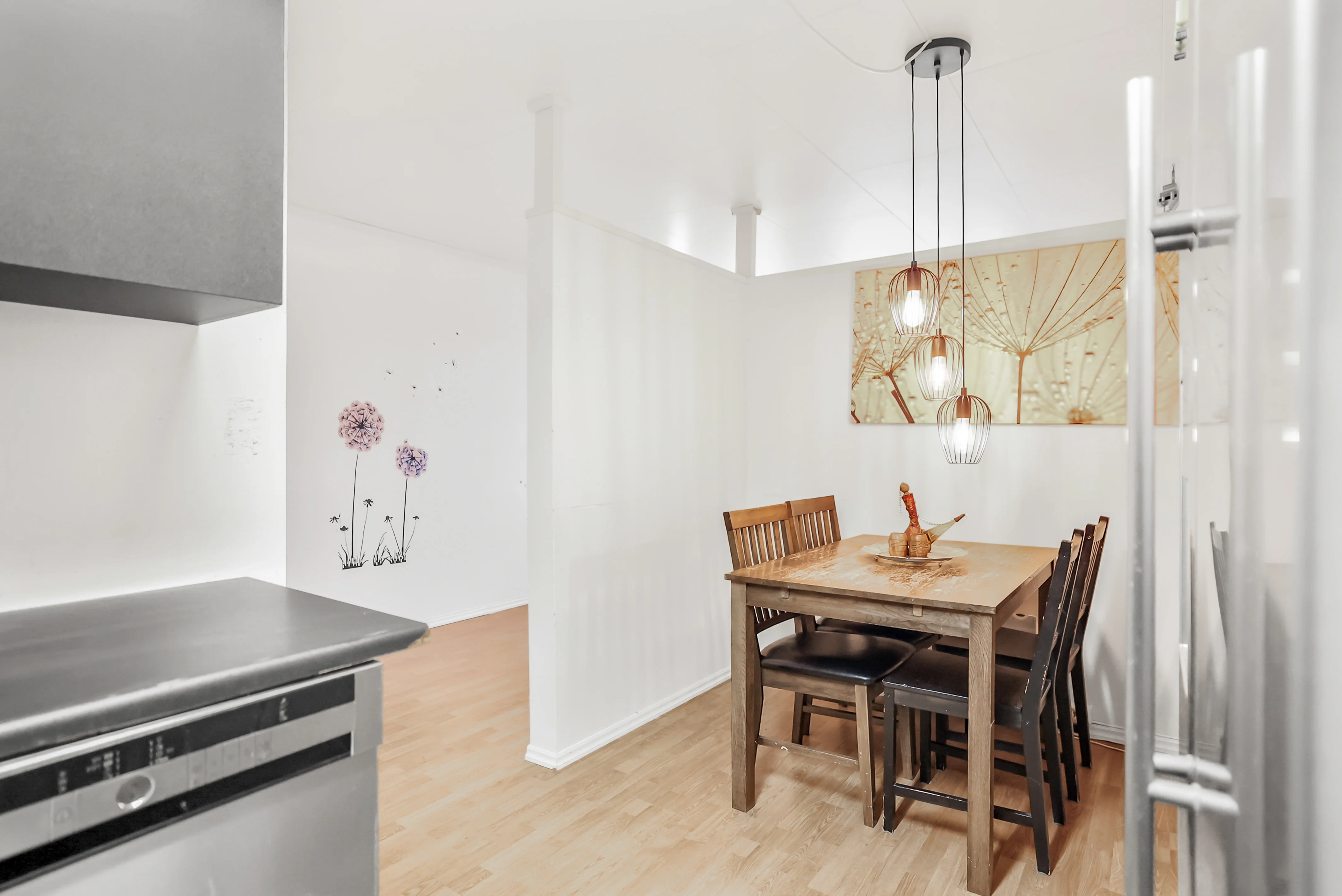 Spiseplass med trebord, seks stoler, og hengelamper over bordet i et lyst rom.