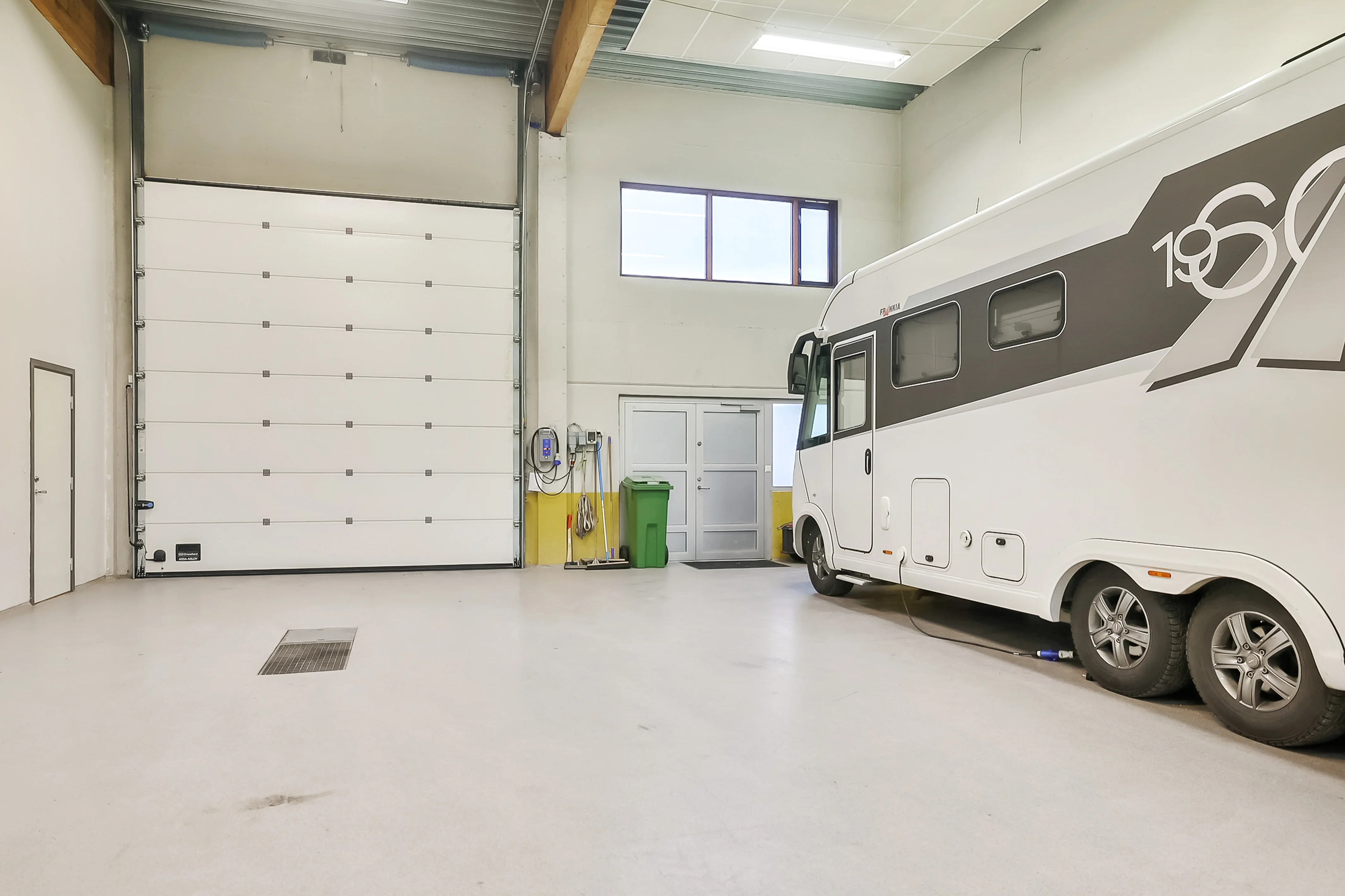 Bobil i lys garasje med hvit port