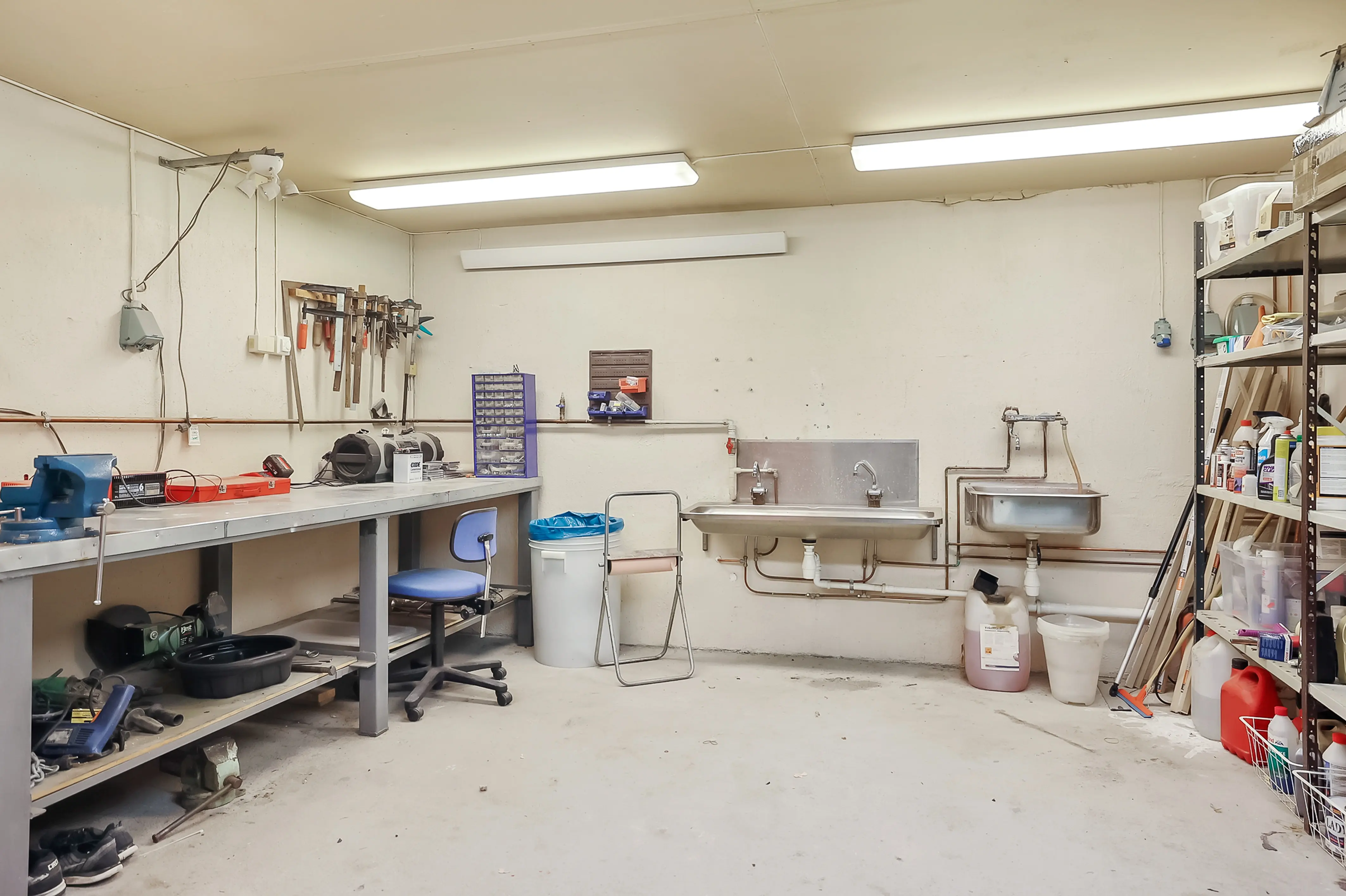 Verksted med arbeidsbenk, verktøy og vaskekummer.